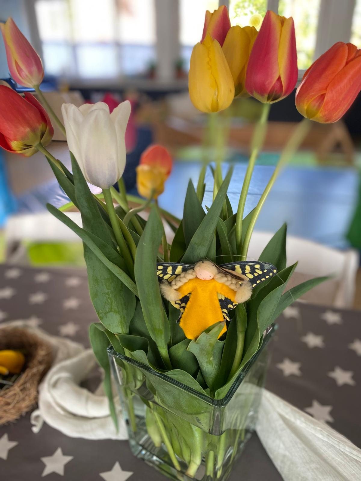 Rote und weiße Tulpen im Glas, dazwischen eine kleine Blütenfee
